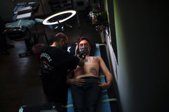 Tattoo parlours in Europe have endured a rough two years during the pandemic.  Pictured, Paul and Friends tattoo parlour in Brussels, where customers wear face masks while they’re worked on. 