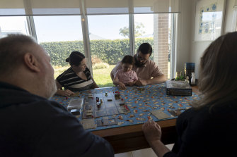Kinsley plays a board game with his wife, daughter and members of the Northwest Sydney Table Top Gamers group, in his dining room.