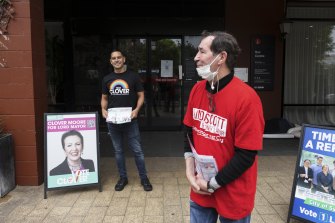 Sydney MP Alex Greenwich, left, who is Clover Moore’s campaign manager, and a Labor supporter hand out how-to-vote cards near a polling station.