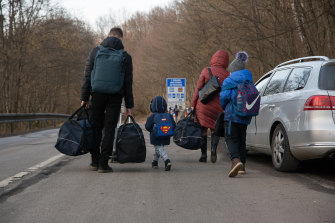 A family carry their bags and walk on the street after they crossed the Slovak - Ukrainian Internatio<em></em>nal crossing border.