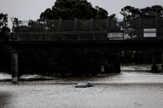 A car is submerged in floodwaters on Henry Lawson Drive in Georges Hall.