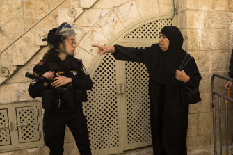 An Israeli police officer stops a Muslim woman before Al -Aqsa Mosque as she attends the second Friday prayer of the Muslim holy month of Ramadan on Friday, April 15, 2022. 