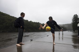 Woronora locals Cody and Jake practise their soccer skills as the rain comes down. 