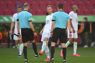 Wolfsburg's Maximilian Arnold taps feet  with the referee and his assistant after the match.