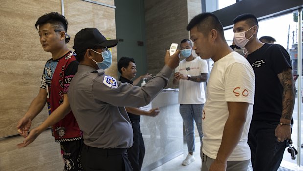 Cambodian security officials take the temperatures of Chinese entering an apartment complex in the Chinatown enclave next to Diamond Island in Phnom Penh.