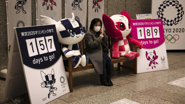 A woman wearing a face mask has her photo taken with the Olympic mascots in Tokyo.