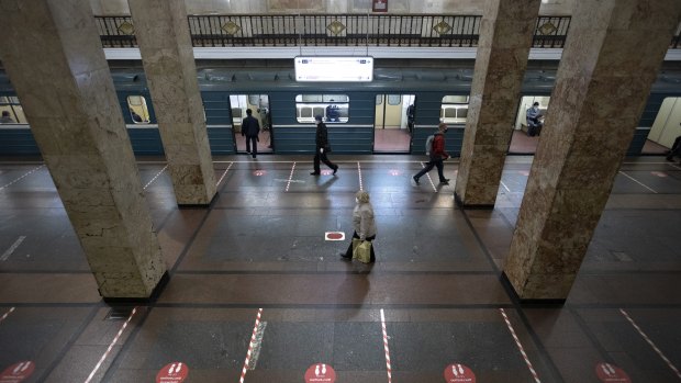 People in Moscow wearing face masks and gloves to protect against coronavirus, observe social distancing guidelines as they walk in the subway.