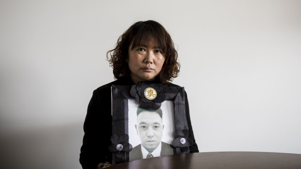 Lihong Wei holds a portrait of her husband Xiaojun Chen, who was killed while working for a delivery company in Sydney.