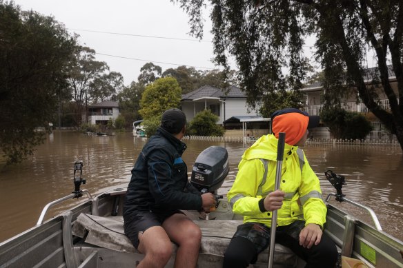 Danny and Ethan make a trip to their home in a tinnie amid heavy flooding in Lansvale.