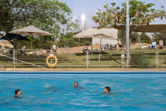 Çocuklar güneş kulesinin yanındaki halka açık havuzda yüzüyor.