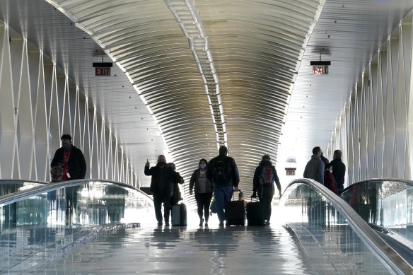 Travellers walking on a pedestrian bridge between terminals at Logan International Airport in Boston.