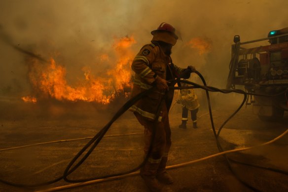 Kundle Moto Rural Fire Service deputy Captain Floyd Goodwin deploys hoses moments before being overwhelmed and forced to retreat behind the truck during the Hillville fire in NSW in 2019.