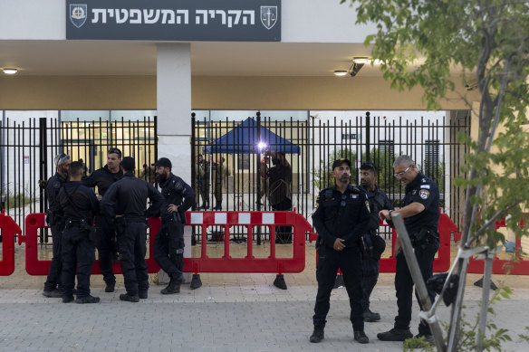 Police officers guard as a worker welds a gate to a military court during a demonstration against Israeli military prosecutors.
