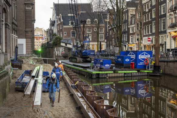 Construction workers rebuilding the crumbling canal wall in the Grimburgwal district of Amsterdam.