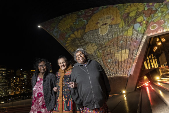 Artists Judith Inkamala, Marlene Gilson and Marlene Rubuntja with the projection of Aboriginal artist Kaylene Whiskey’s work ‘Dolly visits Indulkana’.