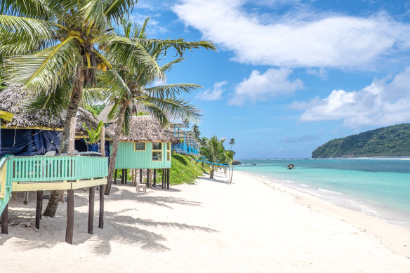 View along Lalomanu Beach of colourful Samoan beach fale huts used as tourist accommodation.