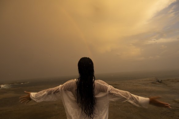 An unidentified woman celebrates the arrival of a summer thunderstorm sweeping over Clovelly on February 10, 2023.