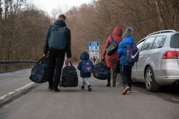 A family carry their bags and walk on the street after they crossed the Slovak - Ukrainian International crossing border.