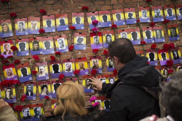 People put red carnations next to photographs during the 87th Spanish Republic anniversary ceremony to pay tribute to people killed in the Spanish Civil War at the Almudena cemetery in Madrid.