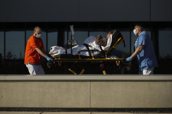 Hospital staff wearing face masks to protect against coronavirus, transfer a patient to MontLegia hospital in Liege, Belgium.
