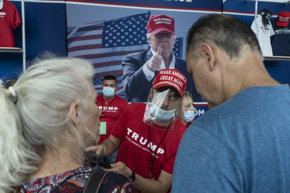 A vendor wearing a protective mask and shield speaks with customers ahead of Trump's rally in Tulsa.