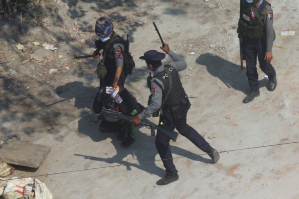 Riot police officers hold down a protester as they disperse protesters in Tharkata Township on the outskirts of Yangon.