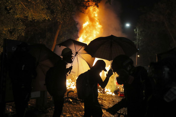 Students walk past a fire that erupted during a clash with police.