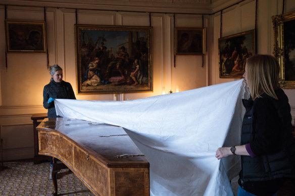 A dust cover is removed from a piano in the Queen’s Drawing Room.