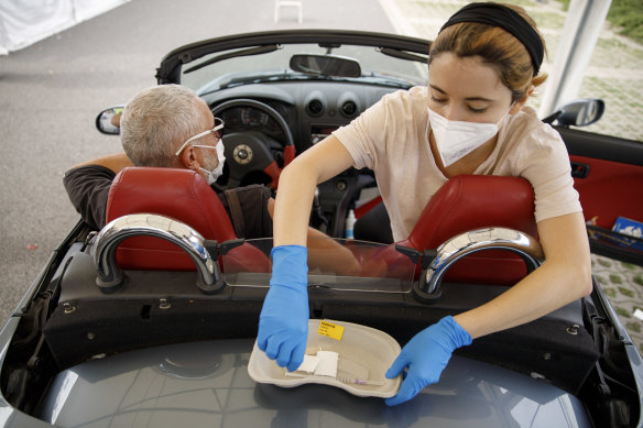 A doctor gives a dose of the Moderna vaccine to a motorist in a drive-in vaccination station in an IKEA car park in Berlin, Germany