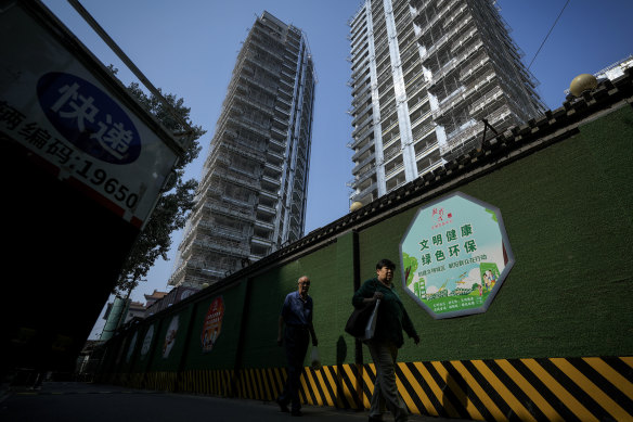 Residents walk by a luxury housing construction site in Beijing.