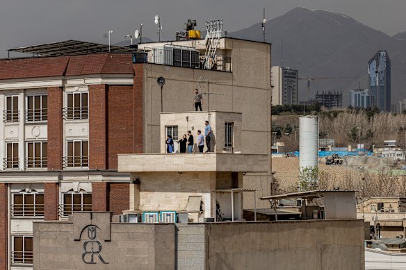 Residents look out from a rooftop vantage point in Tehran, Iran, where large explosions shook the city.