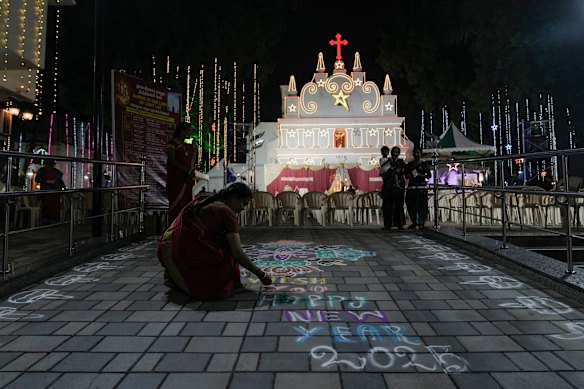 A Christian women prepares a Rangoli, a traditional art work of colored powder, on the eve of New Year at Our Lady of Light Shrine (Luz Church) in Chennai, India.