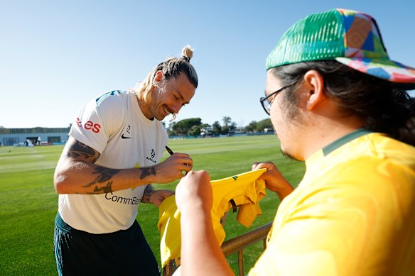 Socceroo Jackson Irvine signs a jersey.