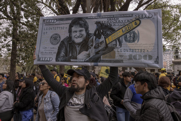 A supporter of Javier Milei holds a replica of a $US100 bill featuring Milei with a chainsaw.