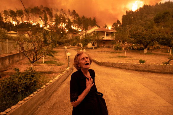 A woman despairs as a wildfire on the island of Evia approaches her house in the village of Gouves. 