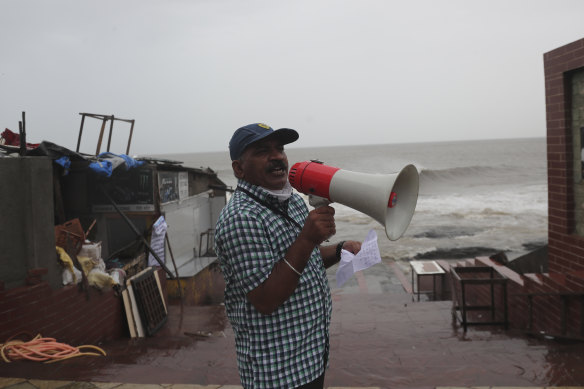 A municipal employee issues an evacuation warning by the shore of the Arabian Sea.