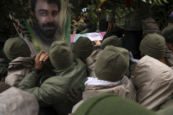 Comrades surround the flag-draped coffin of Revolutionary Guard member Morteza Ebrahimi, seen in poster, who was killed during protests over government-set fuel prices.