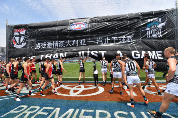 St Kilda and Port Adelaide players run through the banner before the match in Shanghai in 2019.