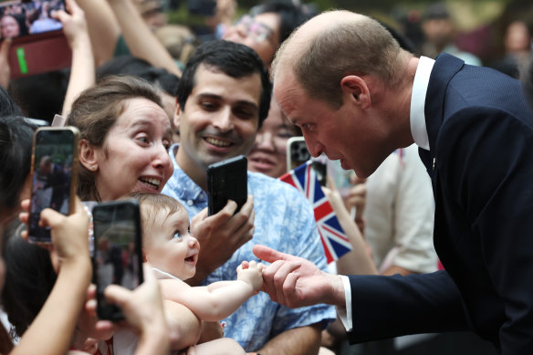 Eight-month-old Albane Costa holds the finger of Prince William, Prince of Wales during his visit to the HSBC Rain Vortex at Jewel Changi Airport in Singapore