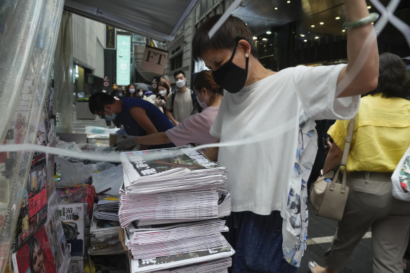 A vender adjusts a stack of last issue of Apple Daily at a newspaper booth in Hong Kong. 
