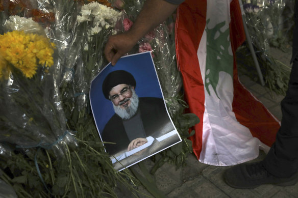 A man places a poster of Hezbollah leader Sayyed Hassan Nasrallah near bouquets of flowers in front of the Lebanese Embassy in Tehran, Iran, on Wednesday.