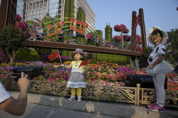 Chinese children pose with Chinese national flags near a floral display for the upcoming 70th anniversary of the founding of the People's Republic of China in Beijing.