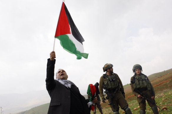 A man waves a Palestinian flag during a protest watched by Israeli soldiers near the Jewish settlement of Bekahot in the Jordan Valley, West Bank, on Wednesday.