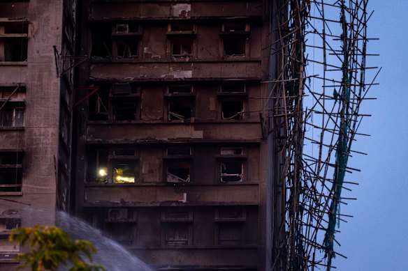 Firefighters with torches search for survivors inside a burnt building in Wang Fuk Court.