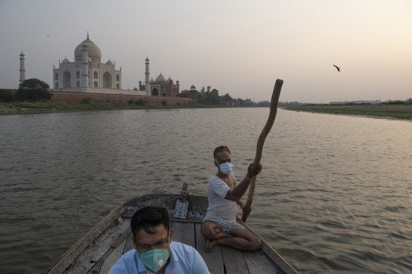 Sumit Chaurasia, left, a guide at the Taj Mahal, in front of the monument in Agra, India, in June, while on the Yamuna river, after the monument reopened. 