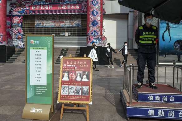 A sign promotes COVID-19 vaccinations, while another by a state-run photo studio offers a 10 percent discount on wedding photos for the inoculated, in Beijing.