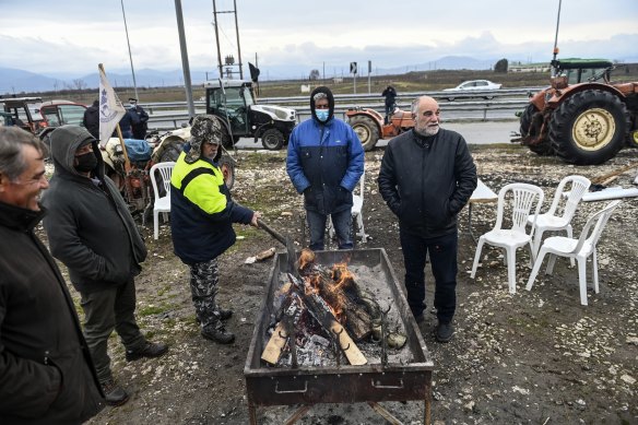 Greece rushed pandemic subsidies to help citizens during the pandemic, but longer term aid is unlikely. Pictured, farmers at the protest warming themselves as they wait. 