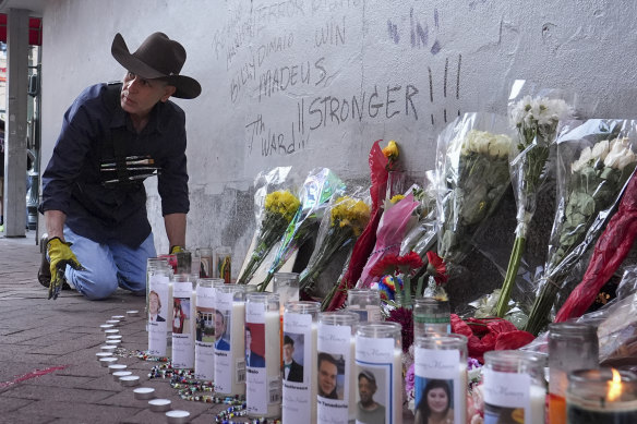 A man adjusts candles and flowers at a memorial to the victims of the deadly truck attack in New Orleans.