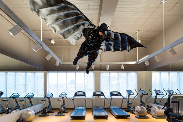 In the gym, a corpulent fibreglass Batman hovers above the treadmills.