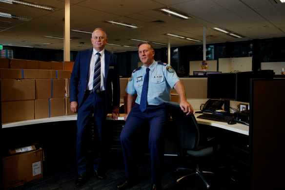 Detective Chief Superintendent Grant Taylor and Assistant Commissioner Gavin Wood sit among evidence boxes for a cold case murder investigation. 